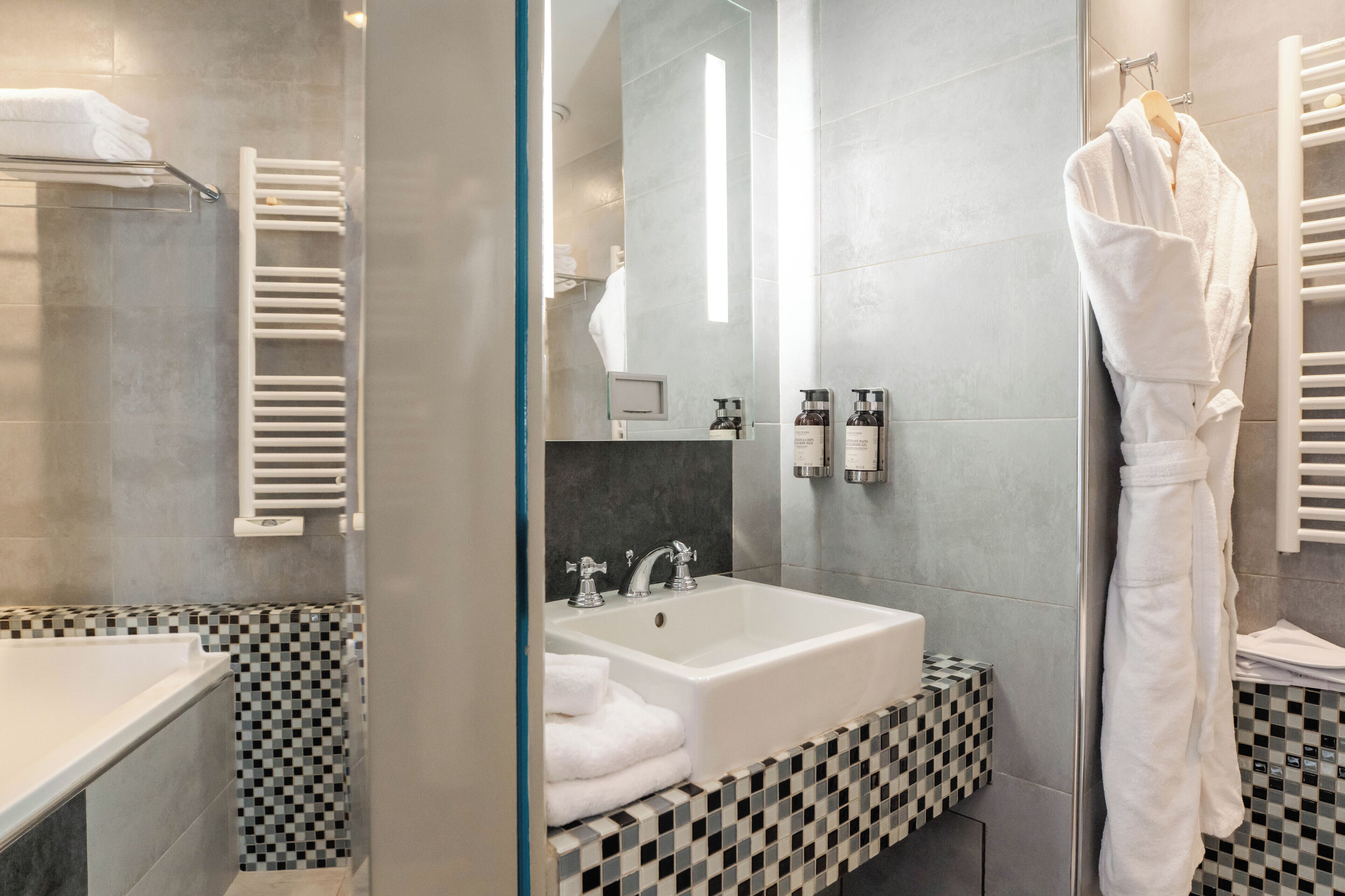 Un bagno moderno con cabina doccia in vetro, un lavandino bianco e un pavimento a scacchi.