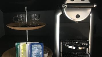 A Nespresso coffee machine with a tray of coffee pods and a small plate with cups and a spoon.