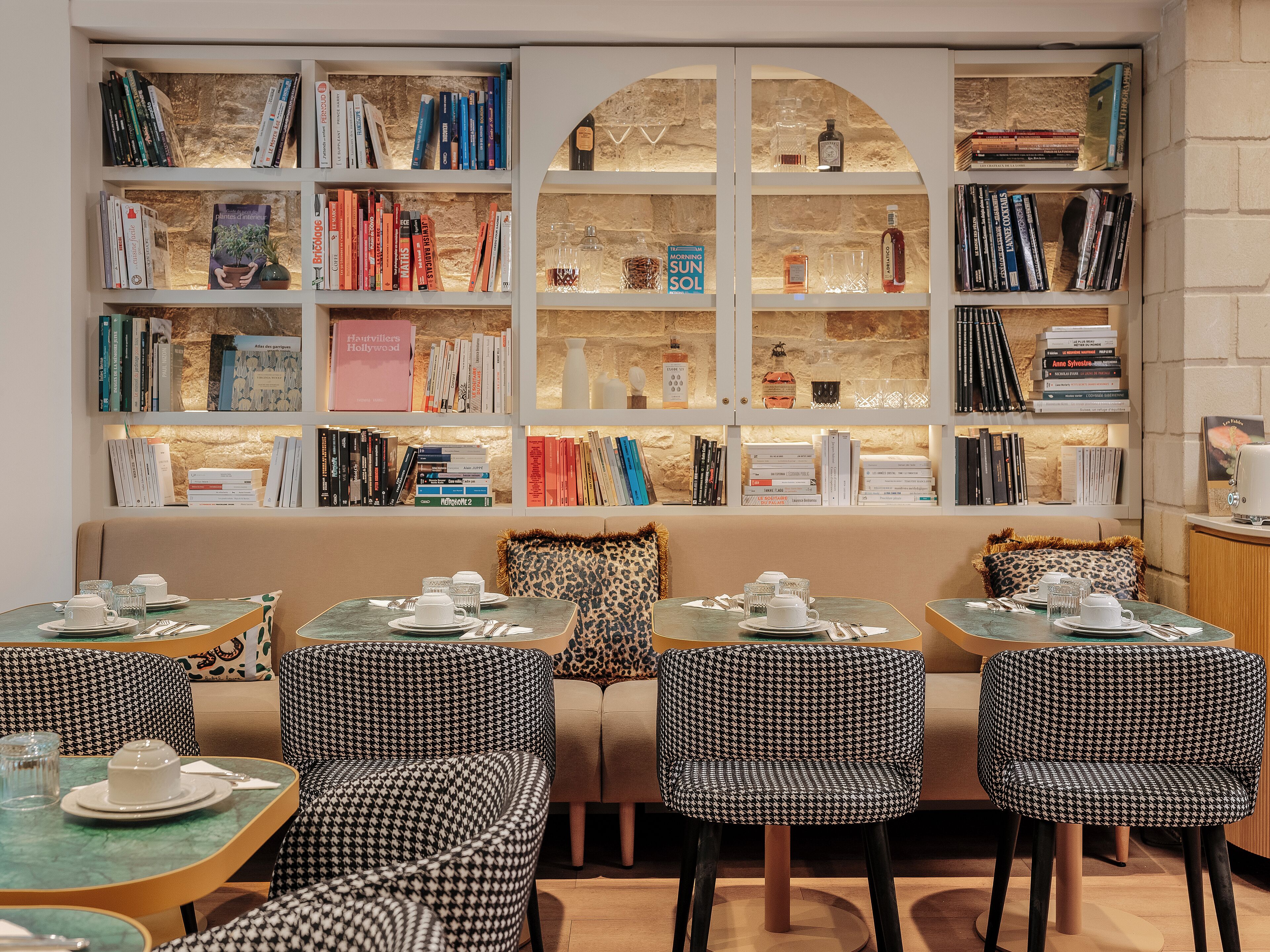 A cozy reading nook with bookshelves, a sofa, and tables set for tea.