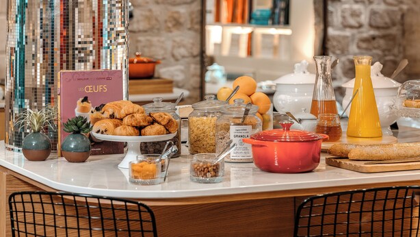 A breakfast buffet with various food items, a book titled 'Les Ceufs', and a stone wall background. - Hotel Zélie Champs-Elysées (Paris)