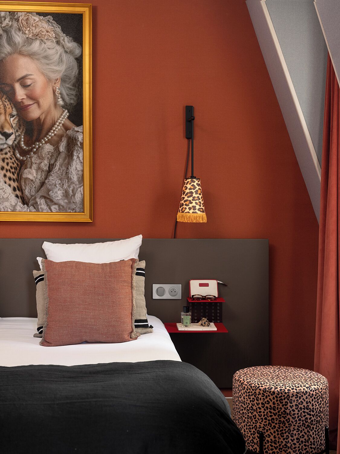 A bedroom with a bed, a nightstand, a lamp, and a painting on the wall.