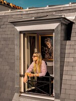 A person sitting by a window with a view of a building's exterior.
