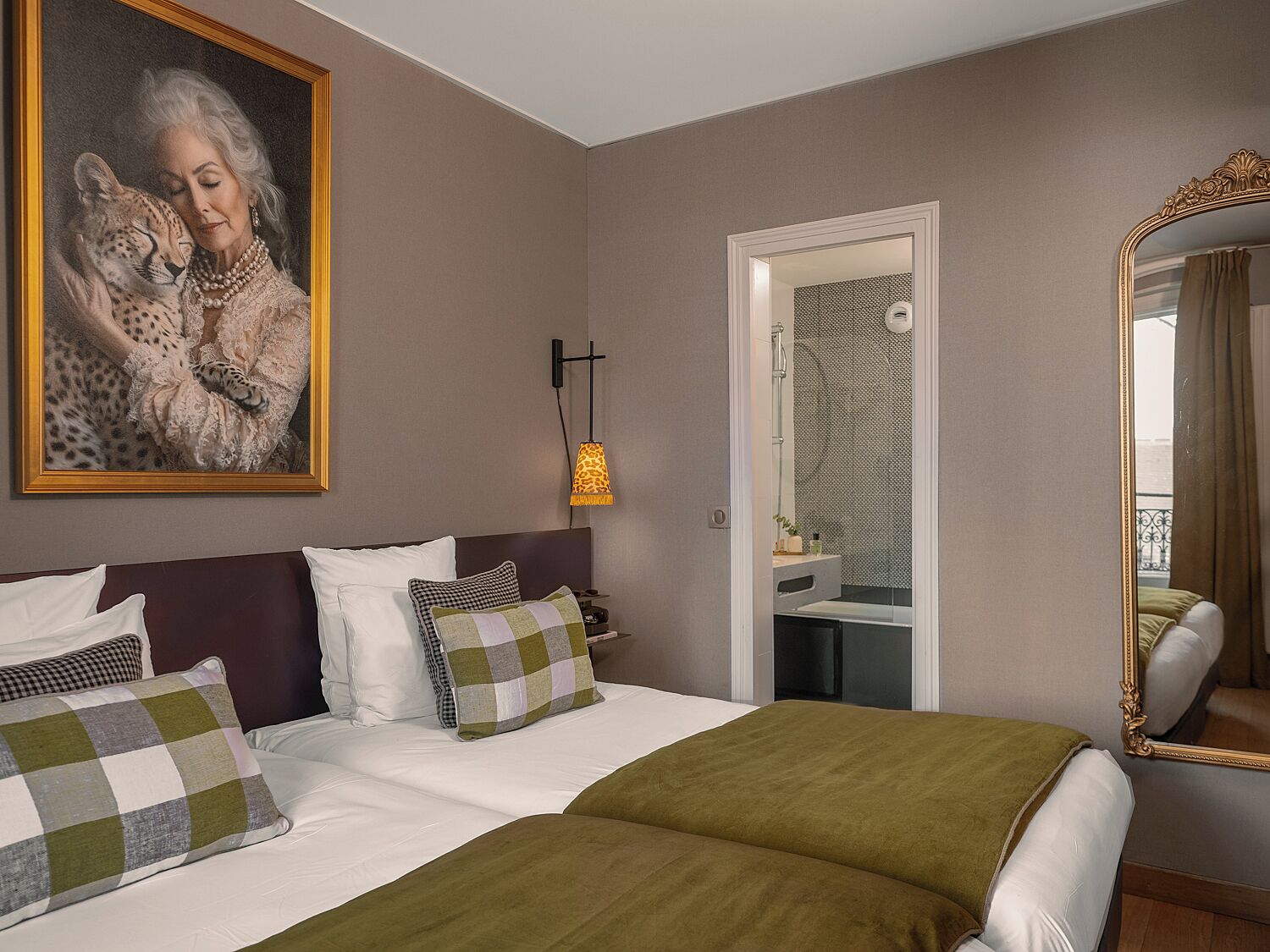 A hotel room with a bed, a painting of a cheetah, a mirror, and a shower area.