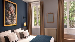 A bedroom with a bed, a painting of a leopard, a mirror, and a window with curtains. - Hotel Zélie Champs-Elysées (Paris)