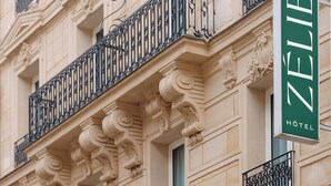 A building facade with ornate architectural details, a green sign indicating a hotel, and a number '23' on the lower left. - Hotel Zélie Champs-Elysées (Paris)