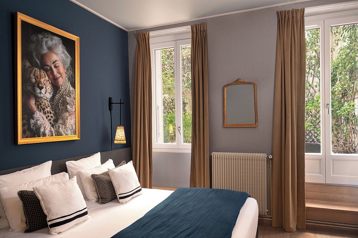 A bedroom with a bed, a painting of a leopard, a mirror, and a window with curtains.