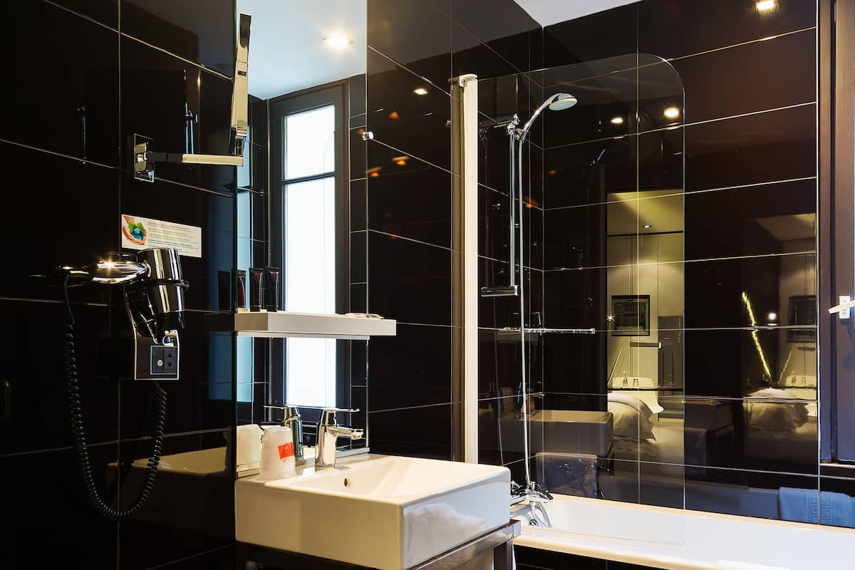 Un baño moderno con un espejo grande, un lavabo y una zona de ducha.