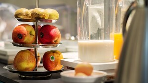 A kitchen counter with a fruit display, a blender, and a glass of orange juice. - Hotel Arc de Triomphe Etoile (Paris)