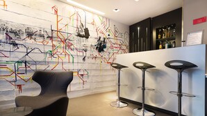 A modern bar area with a unique abstract mural, contemporary bar stools, and a comfortable seating area. - Hotel Arc de Triomphe Etoile (Paris)