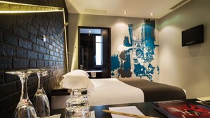 Habitación de hotel con pared de ladrillo, una cama, un escritorio con computadora y un mural en la pared.