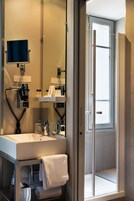 A modern bathroom with a sink, mirror, and glass shower enclosure.