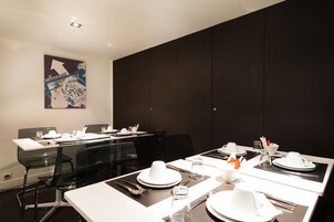 A modern conference room with glass tables, white plates, and black chairs.