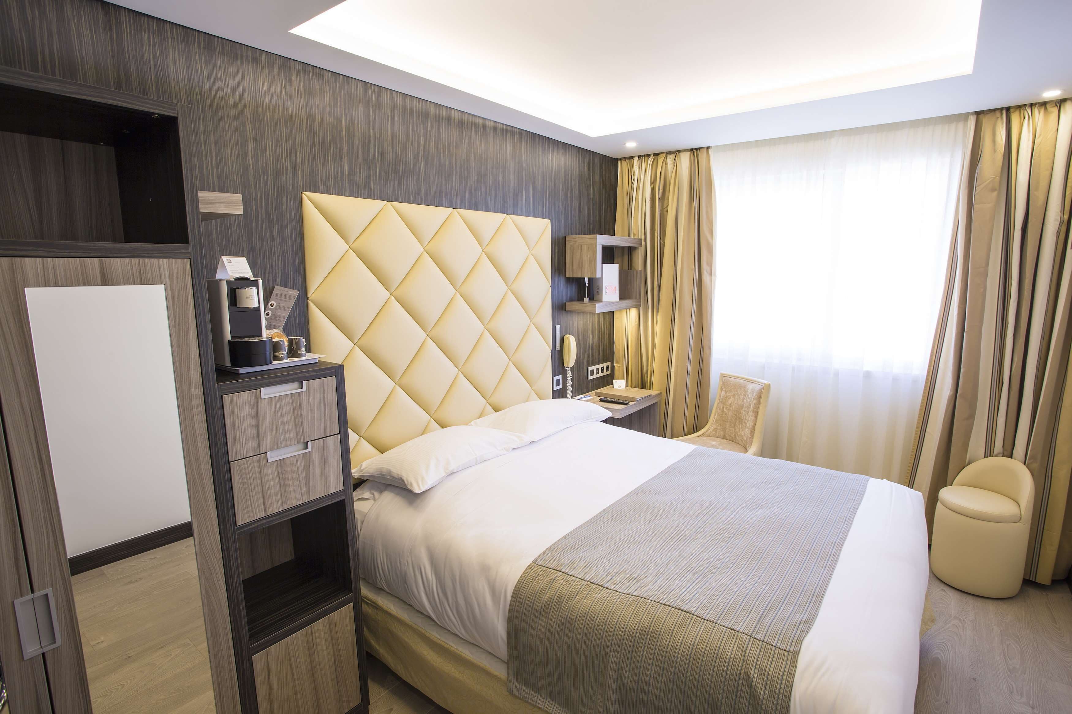Ein Hotelzimmer mit einem großen Bett, einem Schrank, einem Schreibtisch mit Lampe und einer kleinen Sitzecke.