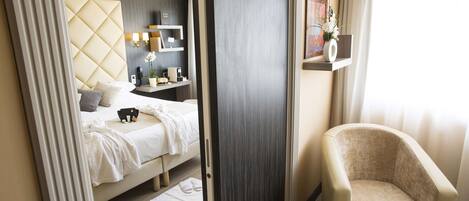 Una habitación de hotel moderna con cama, mesita de noche, silla y un amplio ventanal con cortinas.