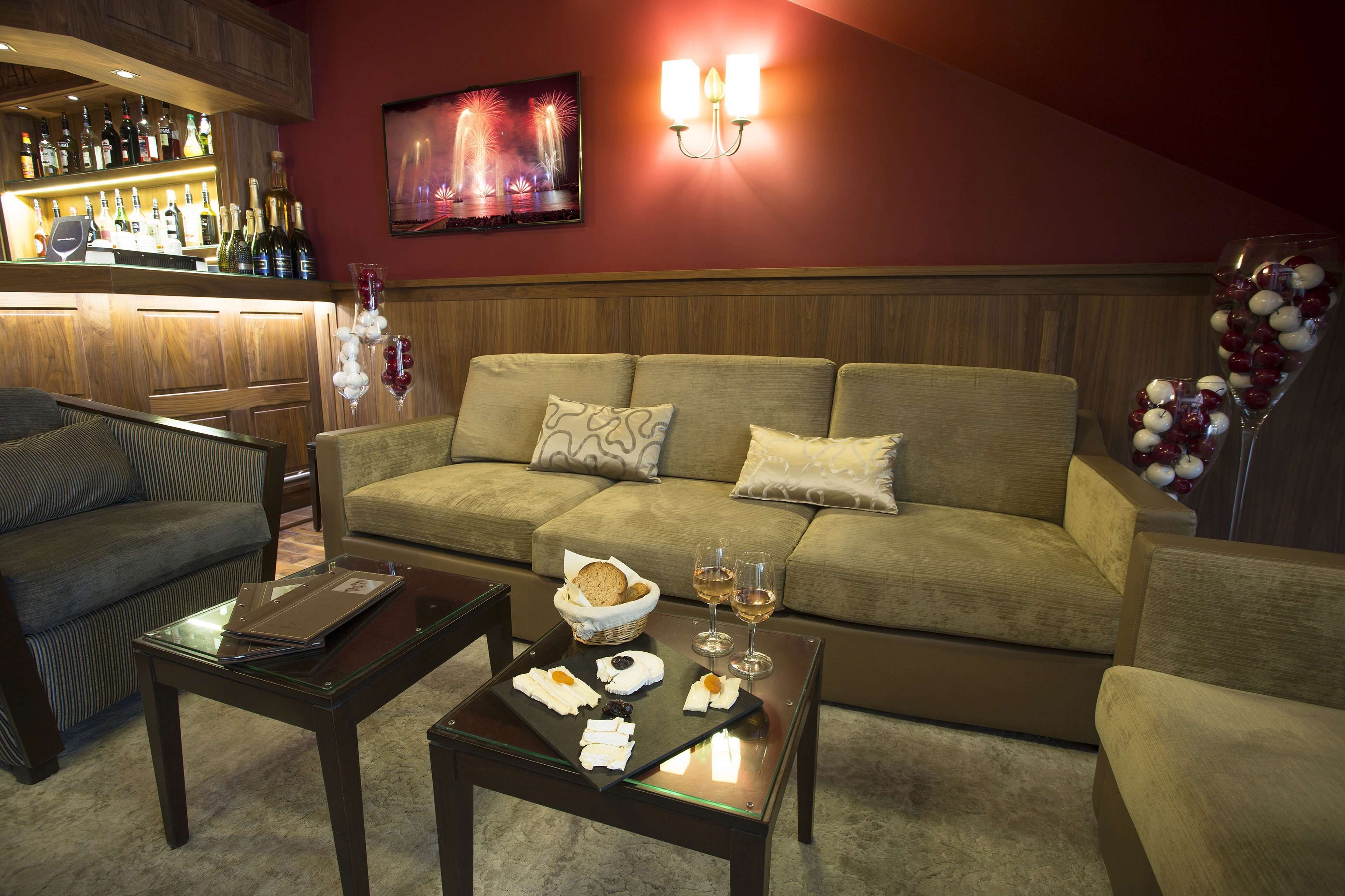 A cozy living area with a sofa, a coffee table with snacks and drinks, a bar with various bottles, and a wall-mounted light fixture.