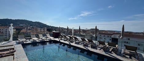Una piscina al aire libre de temporada, sombrillas