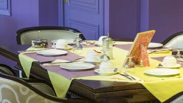 A dining table set with plates, cutlery, and a menu in a room with purple walls and a door.