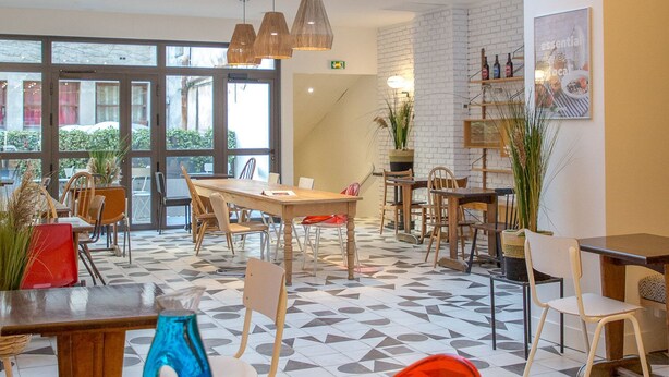 A spacious indoor area with a high ceiling, large windows, and a mix of wooden and metal furniture. - Greet Hotel Marseille Centre St Charles (Marseille)