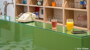 Una habitación con mostrador de recepción verde, estantes de madera con diversos objetos y un teléfono.