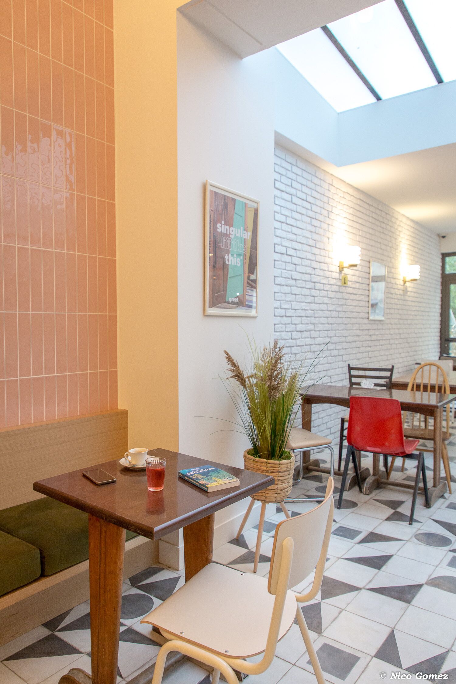 A cafe interior with a tiled floor, wooden tables, and chairs.