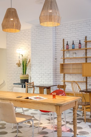 A modern dining area with a wooden table, chairs, and hanging pendant lights. - Greet Hotel Marseille Centre St Charles (Marseille)