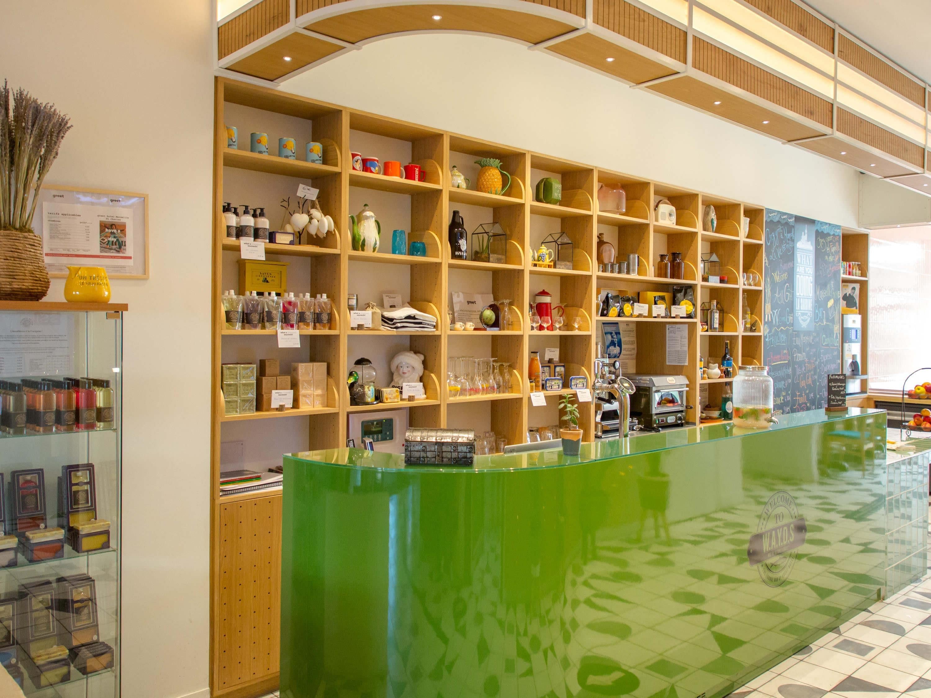 A reception area with a green counter, wooden shelving with various items, and a tiled floor.