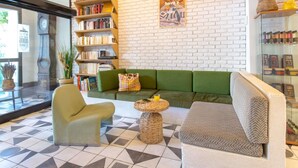 A modern interior with a green sofa, a bookshelf, and a decorative globe on a white brick wall. - Greet Hotel Marseille Centre St Charles (Marseille)