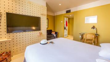Habitación de hotel con una cama grande, un televisor fijado a una pared perforada, un escritorio con una silla y un armario.