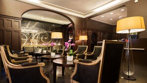 A luxurious lobby with ornate chairs, a round table, and a large lamp. - Hôtel Chambellan Morgane (Paris)