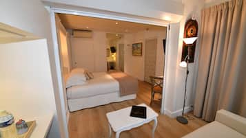 Habitación de hotel con cama, una mesita, una silla, lámpara y dispensador de agua.