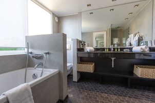 A modern bathroom with a bathtub, a large mirror, and a vanity with a black countertop.