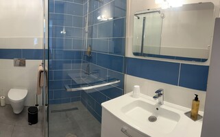 Un bagno con cabina doccia in vetro, lavandino bianco, specchio e water.
