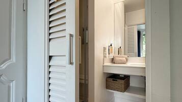 A bathroom with a white vanity, a mirror, and a towel rack.