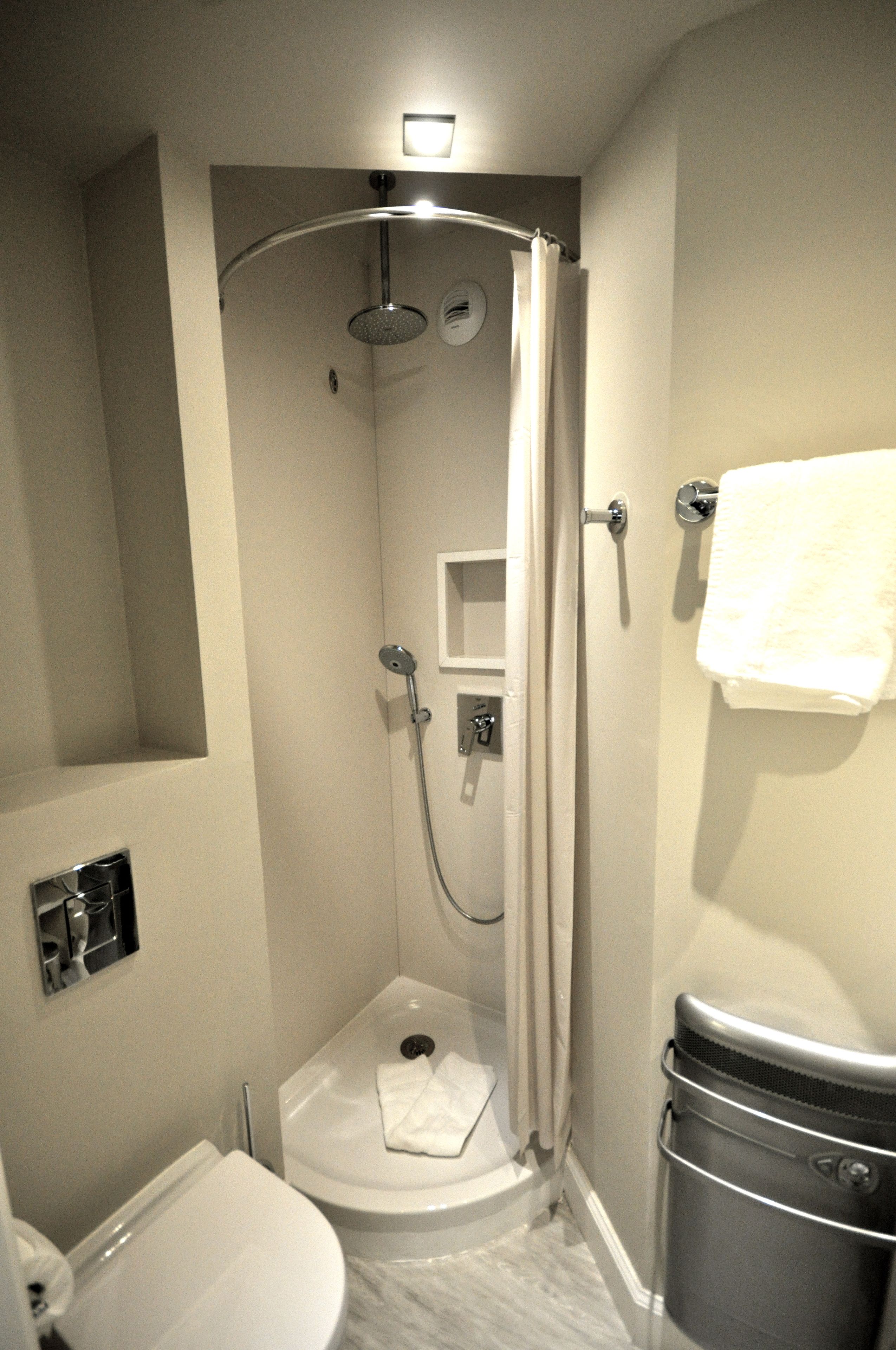 Une petite salle de bain comprenant une douche, des toilettes et un porte-serviettes.