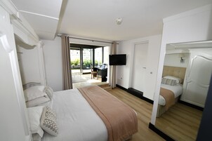 Habitación de hotel con una cama grande, un escritorio, una silla y un televisor en la pared.