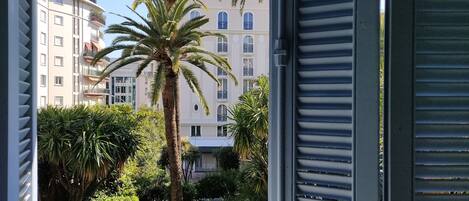 Un balcón con vista a una palmera y un edificio con balcones.