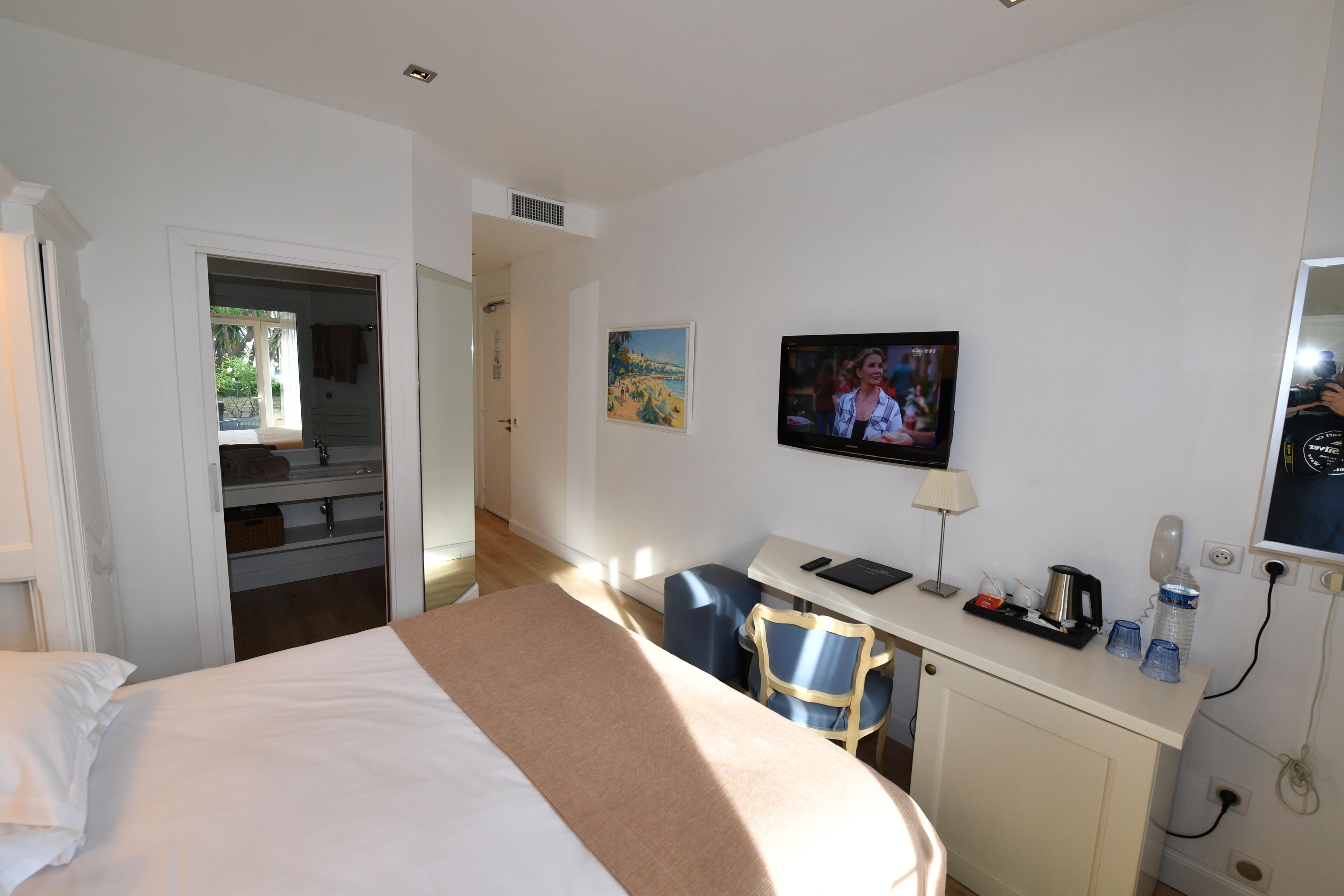 Une chambre d’hôtel avec un lit, un bureau et une chaise, une télévision et un tableau au mur.