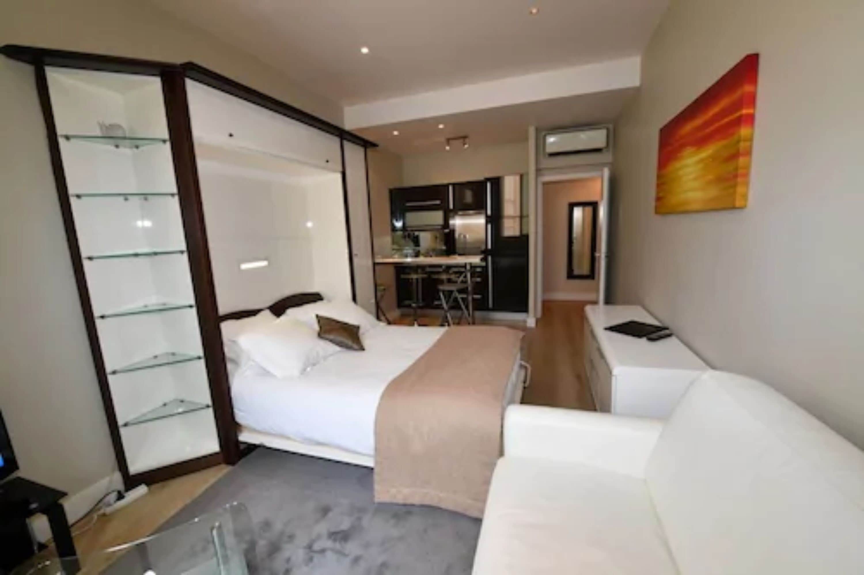 Een moderne slaapkamer met een bed, nachtkastje en een glazen wandplank.