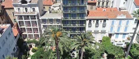 A multi-story hotel with balconies, surrounded by lush greenery and palm trees.