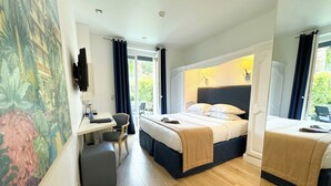 A hotel room with a bed, a desk, a chair, and a large window with curtains.