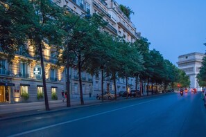 A tree-lined street with a row of buildings, including a hotel with a sign. - Etoile Park Hotel (Paris)