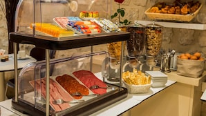 A buffet with various food items and utensils, including meats, pastries, and condiments. - Albe Hôtel Saint-Michel (Paris)