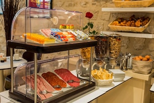 Un bufé con diversos alimentos y utensilios, como carnes, pasteles y salsas.
