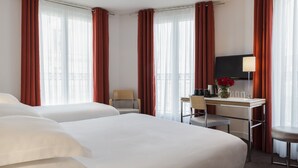 A hotel room with two beds, a desk, a chair, a TV, and a lamp. - Albe Hôtel Saint-Michel (Paris)