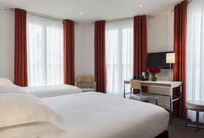 Una habitación de hotel con dos camas, un escritorio, una silla, un televisor y una lámpara.