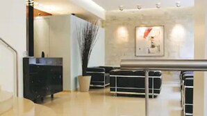 A modern hotel lobby with a reception desk, a staircase, and a potted plant. - Albe Hôtel Saint-Michel (Paris)