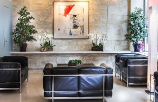 Un vestíbulo moderno con sofás de cuero negro, una pared de piedra y un cuadro abstracto enmarcado.