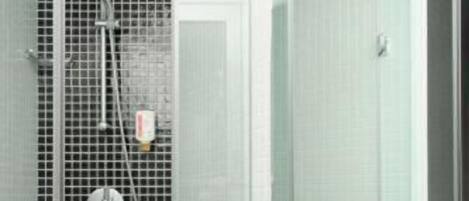 A bathroom with a glass shower enclosure, a white sink with toiletries, and a mirror.