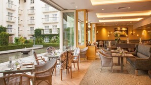A dining area with tables and chairs, a view of a building with balconies, and a small water feature. - The Merrion (Dublin)
