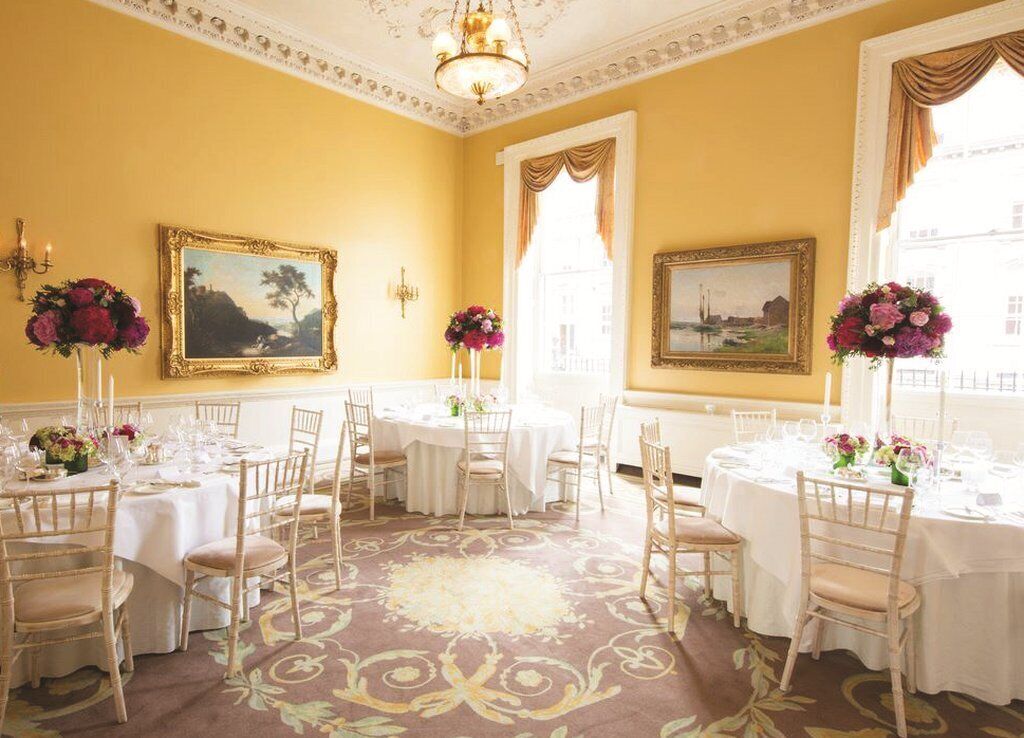 Comedor con mesas redondas, manteles blancos y centros de mesa con flores.